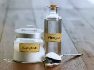 Lọ giấm và hũ baking soda trên bàn gỗ.