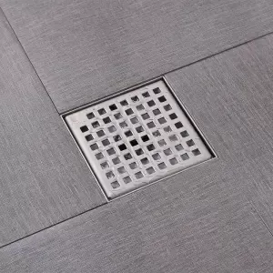Nắp cống thoát nước bằng kim loại trên nền gạch men xám.